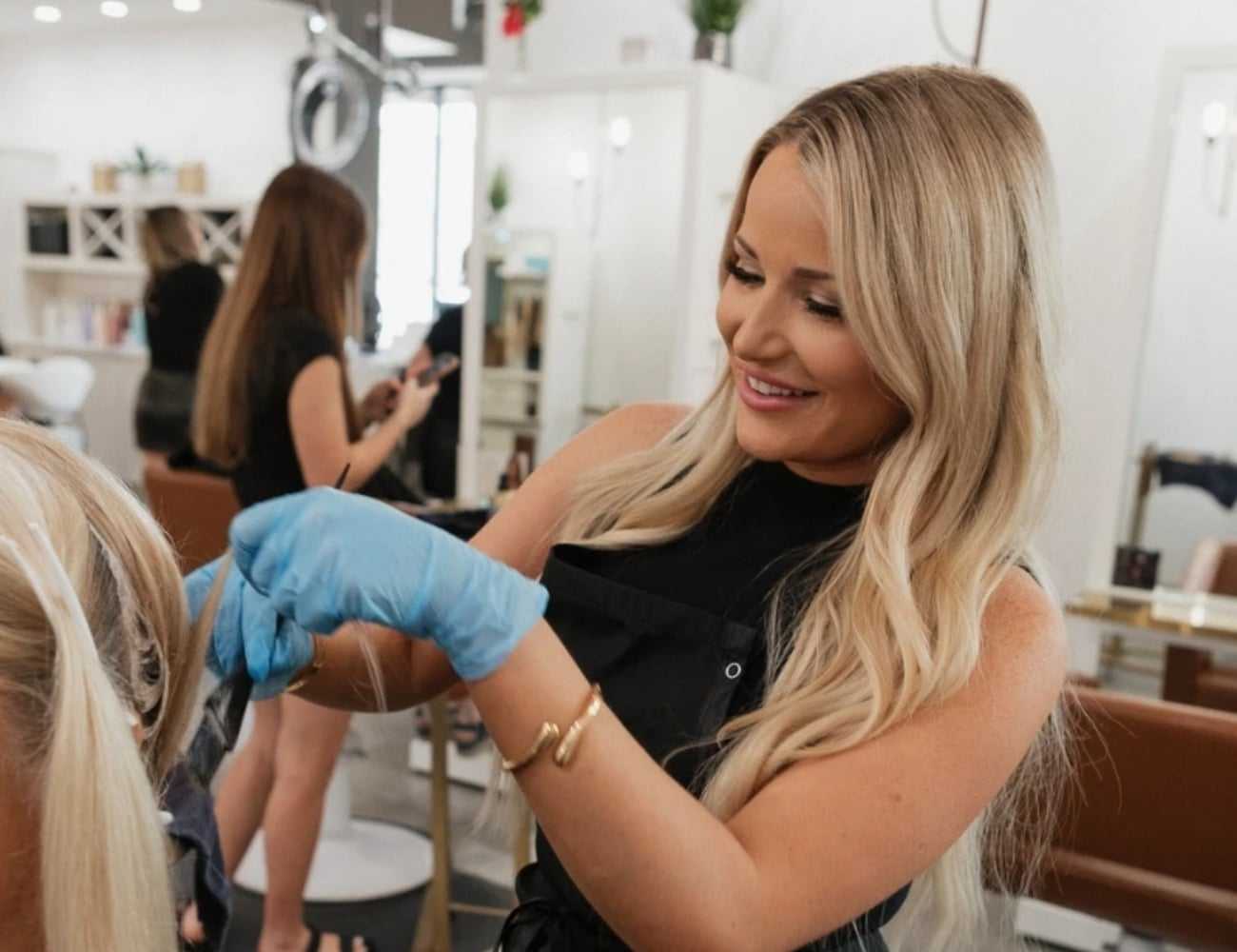 Hairstylist with blonde hair coloring a client's hair in a modern salon.