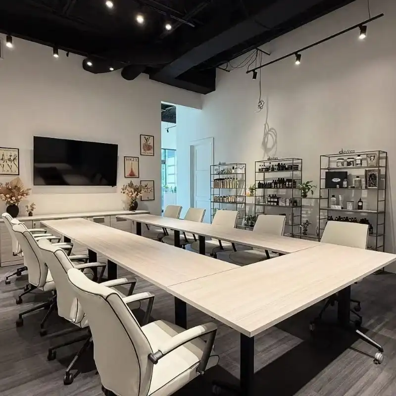 Modern conference room with white chairs, U-shaped table, and shelves displaying decor.