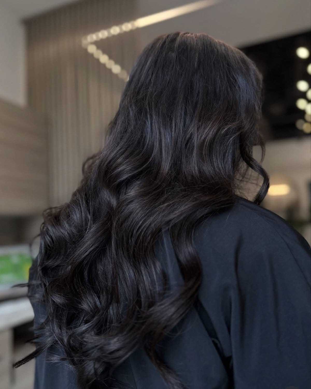 Elegant dark hair with soft curls cascading down the back in a modern setting.