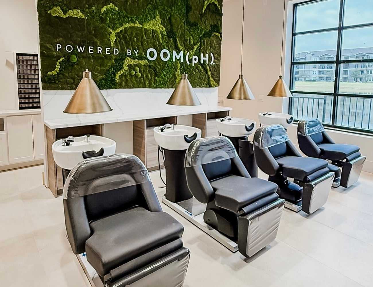 Modern salon wash station with four seats and green wall backdrop.